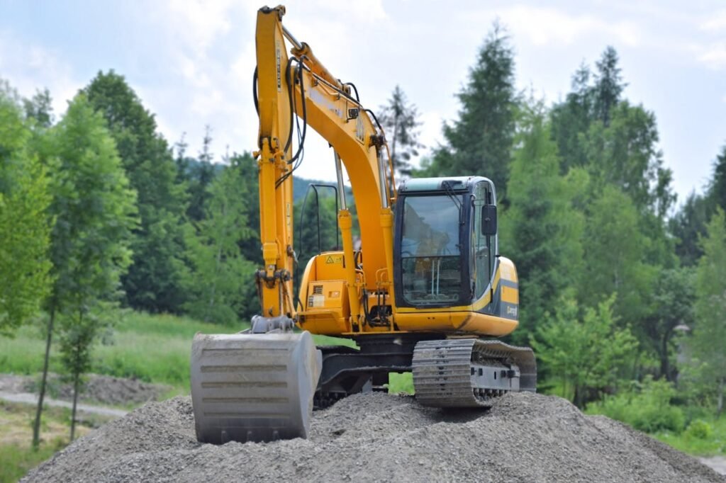 About A yellow excavator on a pile of gravel in a lush, green forest setting in Poland.
